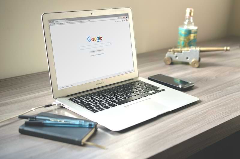 computer aperto su pagina google su scrivania con quaderno, penna e oggetti da scrivania 
