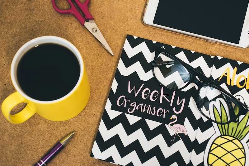 agenda per organizzare la settimana lavorativa, smartphone, tazza di caffè e occhiali da vista su una scrivania