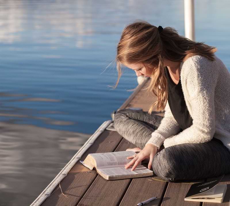 ragazza che legge vicino al lago